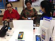 携帯電話販売店で新機種のスマホを手に取る女性。パソコンの所持率が低いインドネシアでは、従来型携帯電話に加えて情報端末として低価格スマホを購入する人も多い＝マルゴシティ（西ジャワ州デポック）
