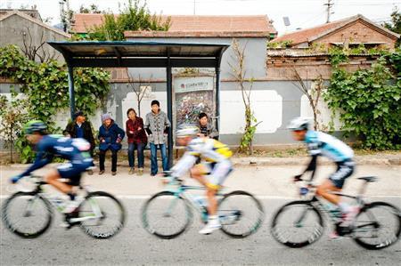 北京市郊外の小さな村を走り抜ける選手たち。住人たちがバス停に座って応援するのどかな光景が見られた＝２０１３年１０月１４日、中国（田中苑子さん撮影）