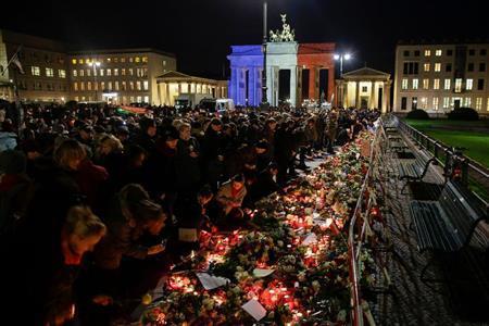 フランス国旗の色にライトアップされた首都ベルリンのブランデンブルク門でテロの犠牲者を追悼する市民ら。世界中のモニュメントがライトアップされた＝２０１５年１１月１４日、ドイツ（ＡＰ）