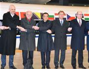 中国上海市の高速鉄道駅で、中東欧各国首脳と握手のパフォーマンスをする中国の李克強首相（中央）＝２５日（共同）