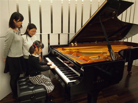 ヤマハのコンサート用グランドピアノ「CFX」を試弾する子供たち＝大阪市西区