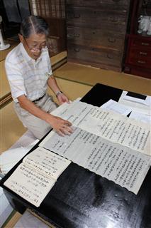 自宅の蔵から見つかった古文書を見る渡辺さん＝甲賀市