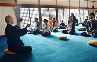 外国人観光客向けに瞑想の体験プログラムを教える僧侶の田村暢啓さん(左端)=4月、和歌山県高野町 外国人観光客向けに瞑想の体験プログラムを教える僧侶の田村暢啓さん(左端)=4月、和歌山県高野町