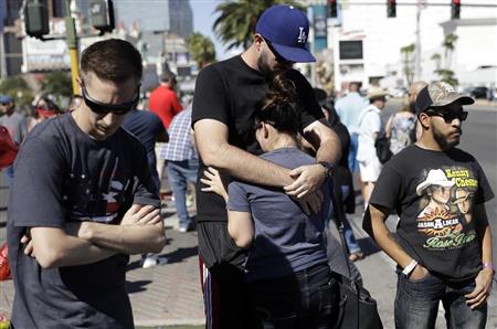 ２日、銃乱射事件の発生した米・ラスベガス中心部の目抜き通りで、抱き合って悲しむカップル（ＡＰ＝共同）