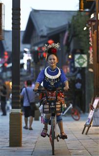 貴州省でモバイクの自転車に乗るミャオ族の女性(中国新聞社) 貴州省でモバイクの自転車に乗るミャオ族の女性(中国新聞社)
