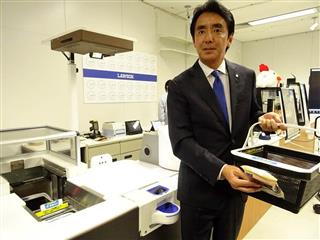 開発中の「次世代店舗」を紹介するローソンの竹増貞信社長。商品のバーコードを買い物カゴ付属のリーダーで読み取り、無人レジで精算する(2017年12月4日、東京都港区港南の「ローソンイノベーションセンター」) 開発中の「次世代店舗」を紹介するローソンの竹増貞信社長。商品のバーコードを買い物カゴ付属のリーダーで読み取り、無人レジで精算する(2017年12月4日、東京都港区港南の「ローソンイノベーションセンター」)