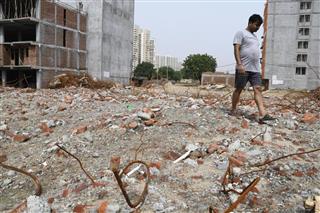 ニューデリー近郊シャーベリ地区で集合住宅ビル2棟が倒壊した現場跡を歩く人=8月7日(共同) ニューデリー近郊シャーベリ地区で集合住宅ビル2棟が倒壊した現場跡を歩く人=8月7日(共同)