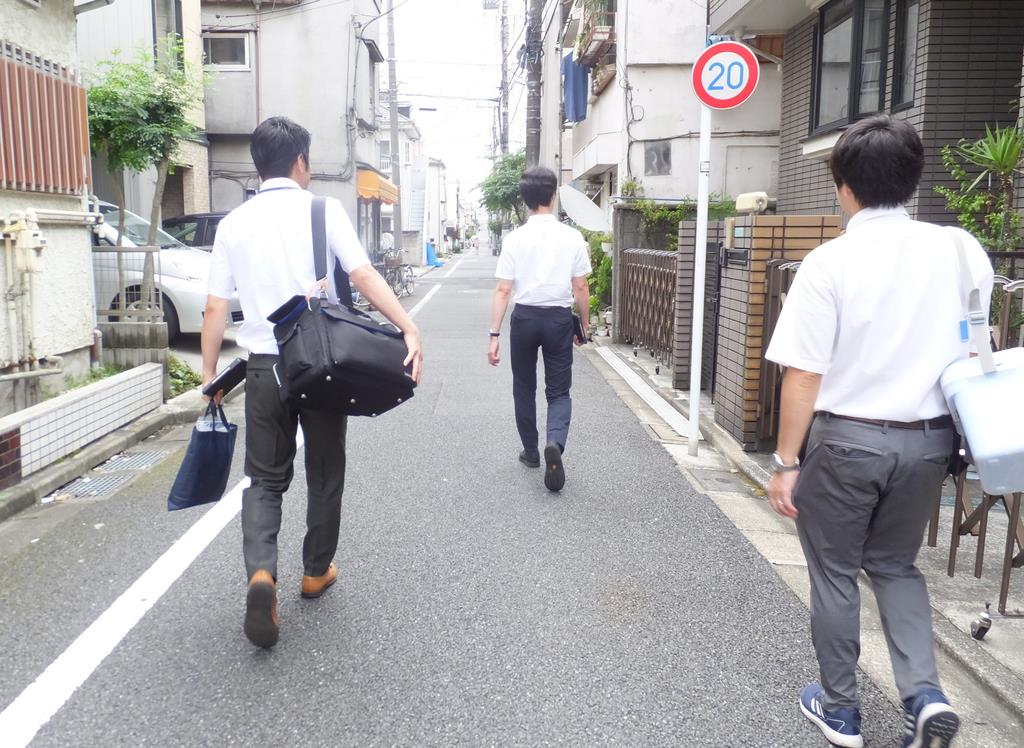 医療器具が詰まった重いかばんを肩に、医師に伴い患者のもとへ。住宅街をゆく２人のＰＡ（右、左）＝東京都練馬区