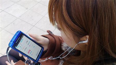 スマートフォンを使ってネットラジオを聞く女性。技術の進歩で、ラジオも次々と進化している＝２０１１年１２月１６日（明治大学・小池保夫ゼミ有志学生記者撮影）