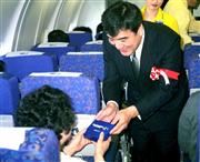 スカイマークの機内で記念品を配る澤田さ（平成１１年４月）
