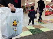 ハチのイラストが描かれた回収袋を手にイズミヤ枚方店で買い物する来店客＝大阪府枚方市