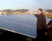 ソーラーパネルと植物プラントドームを見渡す半谷栄寿さん＝福島県南相馬市（半谷さん提供）