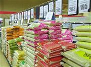 ジャポニカ米の品薄が続くスーパーで、品ぞろえが豊富なタイ米が大量に積み上げられたコーナー。店員は「値段はこれまでどおり」と言うが