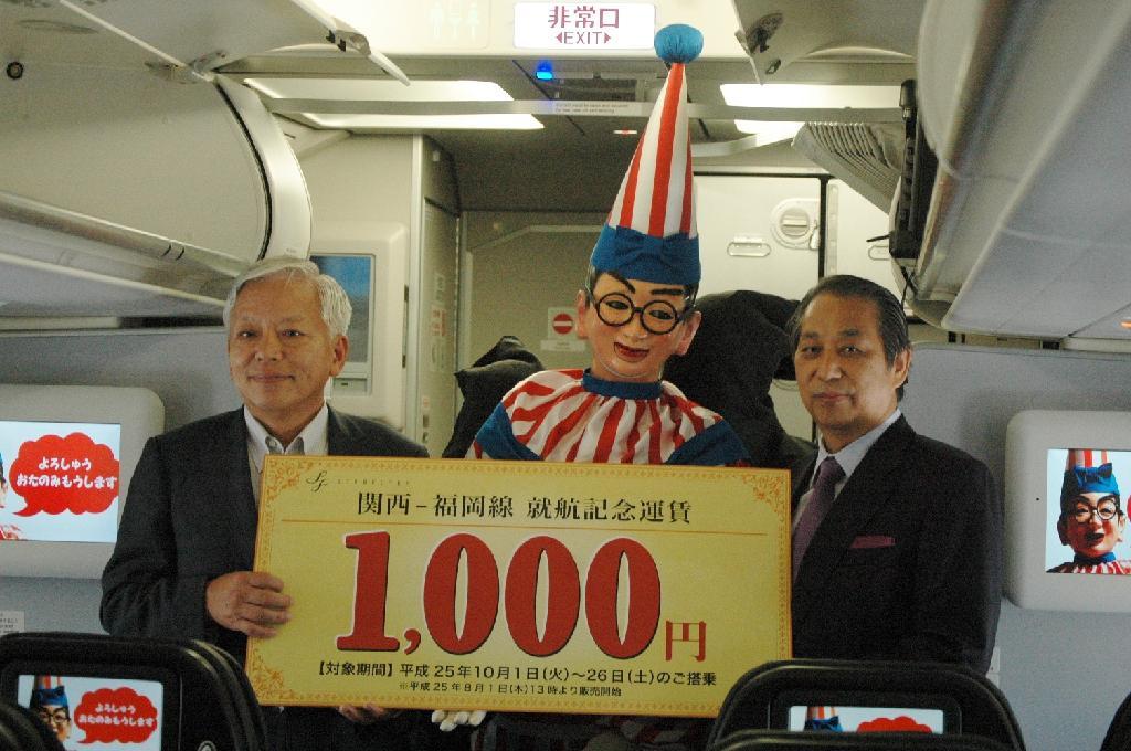 大阪・道頓堀名物「くいだおれ太郎」と関空－福岡線の開設を発表するスターフライヤーの米原慎一社長（右）ら＝７月３０日、関西国際空港