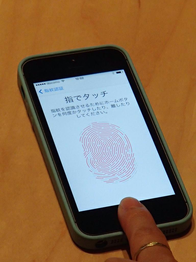 アップルの国内メディア向けのイベントで公開されたアイフォーン５ｓ。ホームボタンをタッチして指紋を登録する＝１１日、東京・六本木