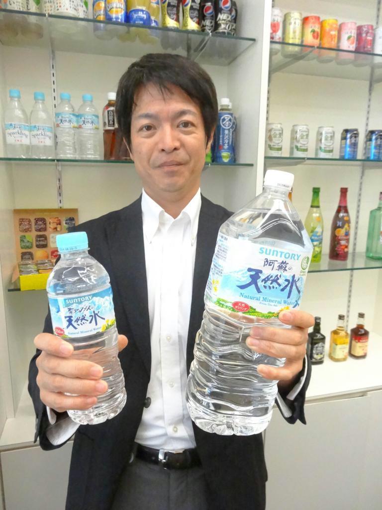 「サントリー天然水」のペットボトルを手に「消費者の声が『最軽量化』の後押しになった」と語る岸重信部長