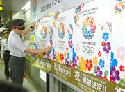 東京五輪の招致ポスターをはがし、開催決定を祝うポスターに張り替える駅員＝９月１０日午後、東京都新宿区の都営地下鉄大江戸線都庁前駅