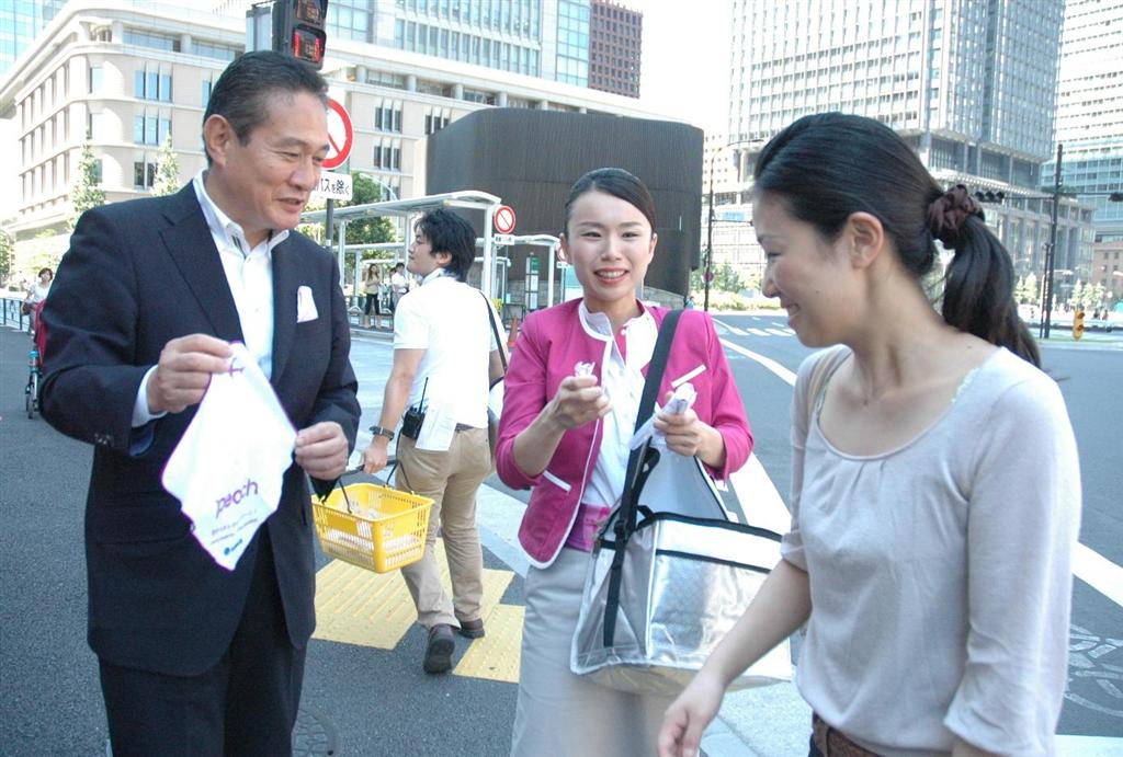 通行人に冷たいおしぼりを配り、関空－成田線をＰＲするピーチ・アビエーションの井上慎一最高経営責任者（左）ら＝８月２８日、東京・丸の内