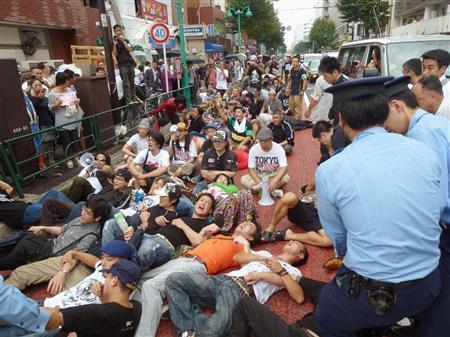 道路に寝転び、ヘイトスピーチデモを妨害する人たち＝９月８日、東京都新宿区（共同）