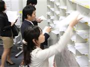 決算資料をマスコミ各社のボックスに投げ込む各企業担当者ら＝３１日、中央区日本橋兜町の東京証券取引所