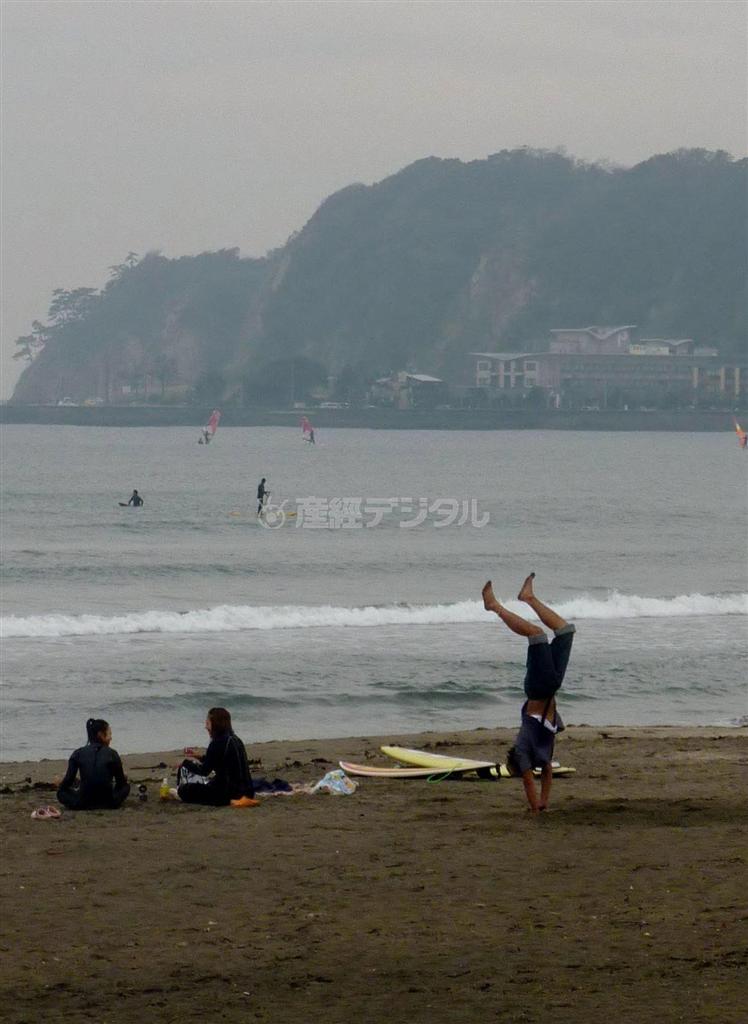 休憩を取るサーファーの傍らでは、なぜか逆立ちをしている人もいた＝１１月４日、神奈川県鎌倉市