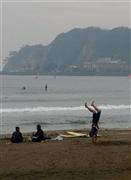 休憩を取るサーファーの傍らでは、なぜか逆立ちをしている人もいた＝１１月４日、神奈川県鎌倉市