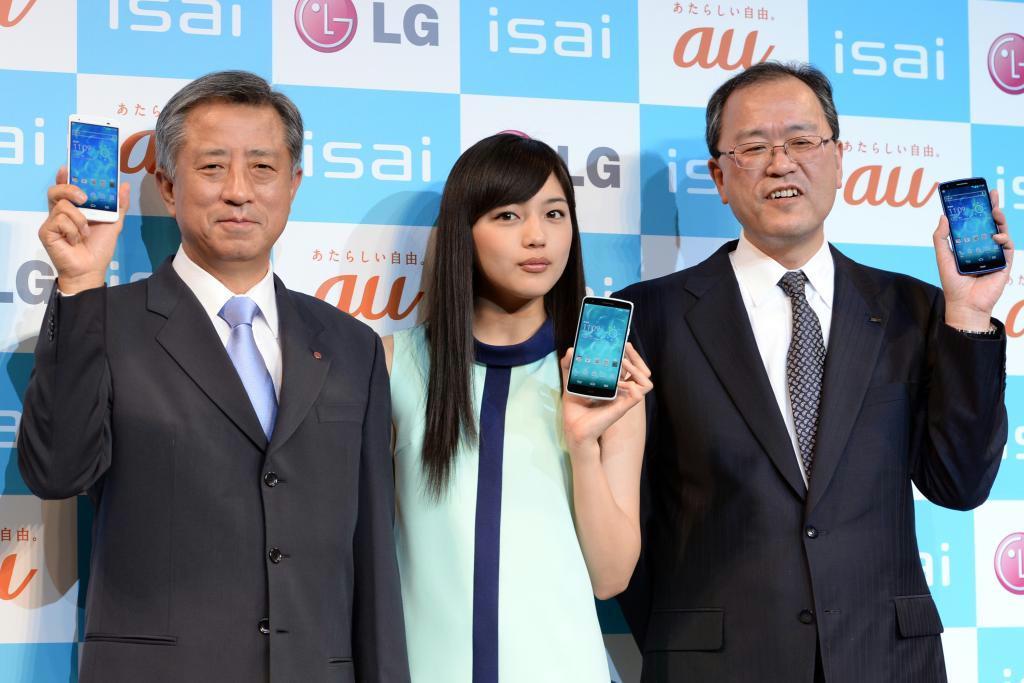 スマートフォン「ｉｓａｉ」をアピールする（左から）ＬＧエレクトロニクスジャパンの李揆弘社長、ＣＭキャラクターで女優の川口春奈さん、ＫＤＤＩの田中孝司社長＝２０日午前、東京都港区