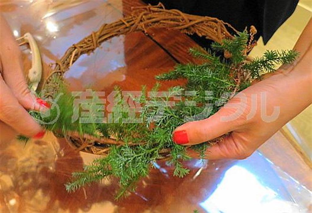 （手順１）ツルでできた既製のリース土台に、ヒムロ杉の枝を添わせるように巻き付け、上からワイヤを巻き、留めていきます（提供写真）