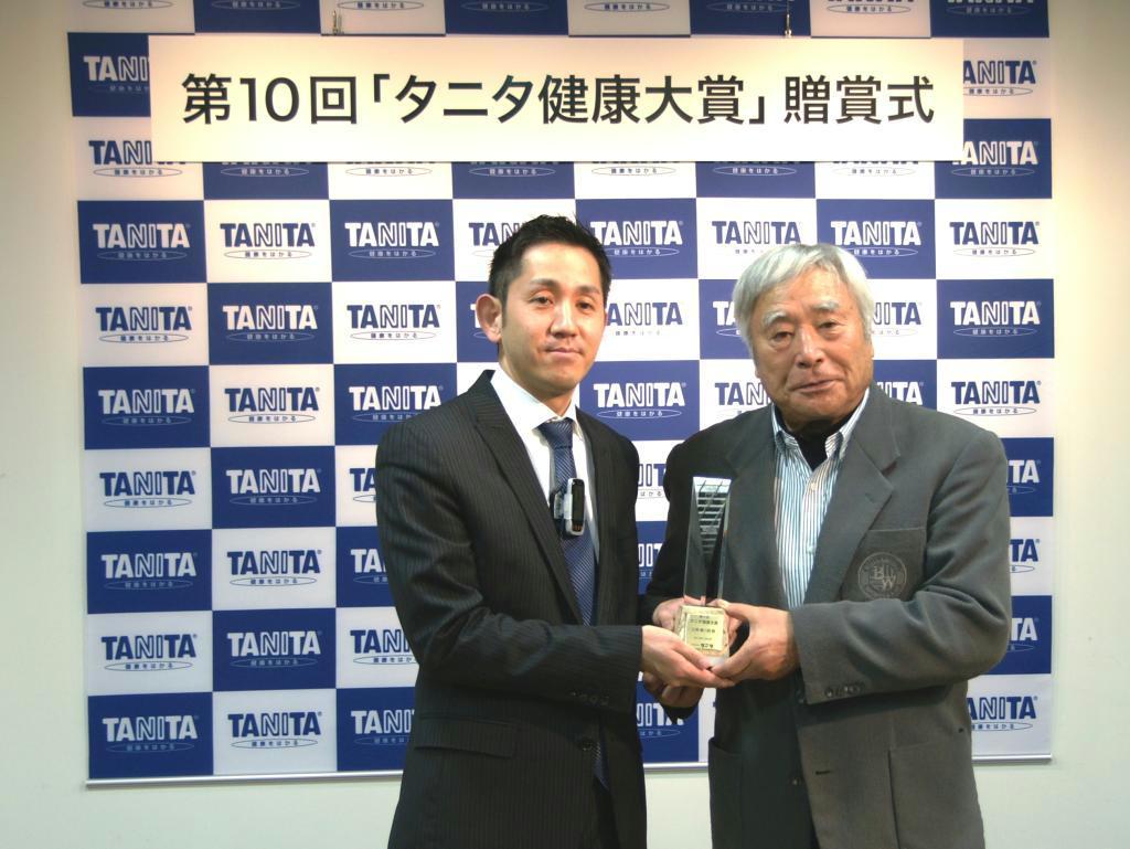 タニタの谷田千里社長（左）から大賞のトロフィーを授与される三浦雄一郎氏＝３日、東京都内