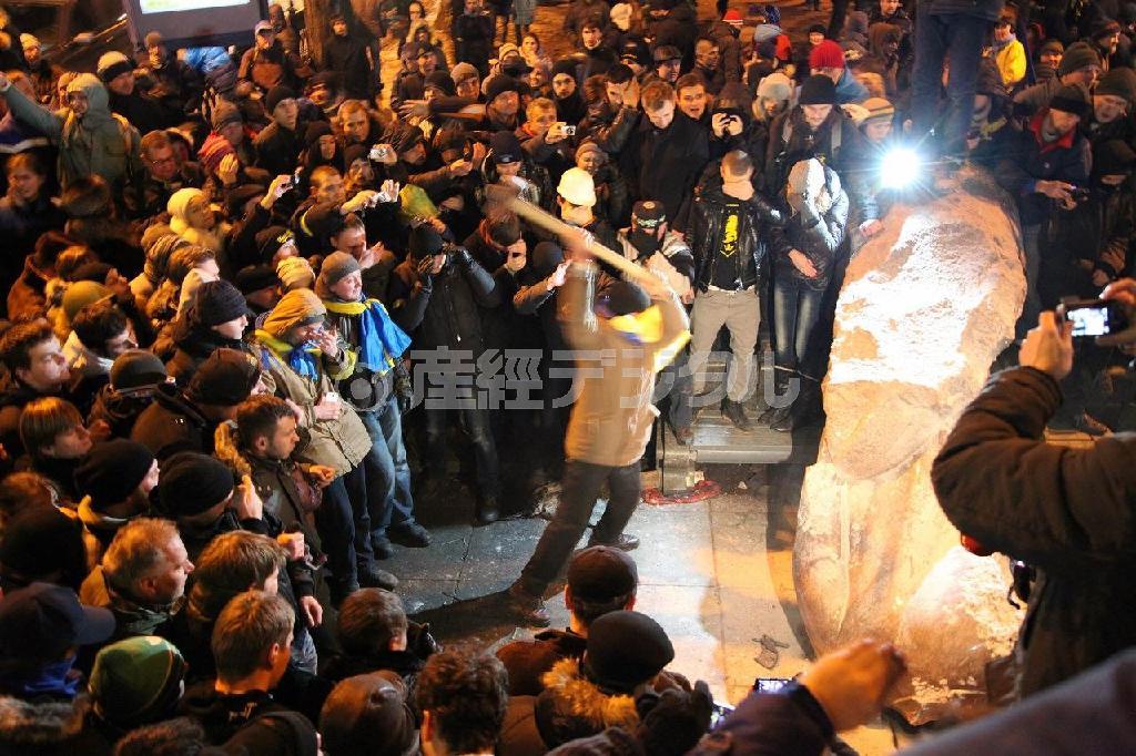 １２月８日夜、首都キエフ中心部でなぎ倒されたウラジーミル・レーニン像をハンマーで叩く男性。「われわれはＥＵ（欧州連合）と共にある」と周囲から歓声があがった＝２０１３年、ウクライナ（佐々木正明撮影）