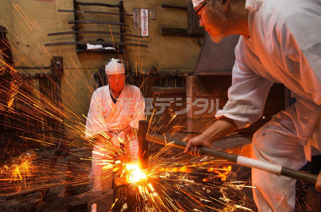 正宗２４代目の山村綱廣さんの指示でお弟子さんが槌を振り下ろす。四方に火の玉が飛び散った＝２０１３年１２月８日、神奈川県鎌倉市御成町の正宗工芸（渡辺照明撮影）