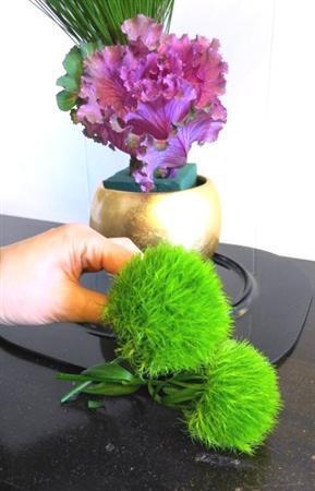 （手順２）松の根元にハボタンを低めに入れます。次に、器の縁を囲むように、丸いテマリソウを５本挿して、アレンジに安定感を加えます（提供写真）