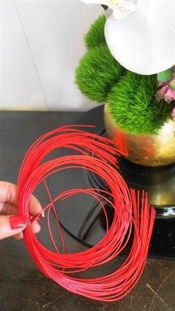 （手順４）赤い水引きを輪っか状にして、最後に胡蝶蘭のななめ下あたりにアクセントとして加えます（提供写真）