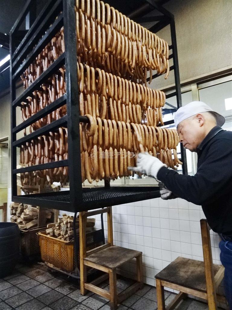 現在も現役の職人として現場に立つ嶋田耕治さん。一つ一つていねいに確認し、ソーセージのつなぎ目をはさみで切っていく作業＝２０１３年１２月１８日、秋田県大仙市（今泉有美子撮影）