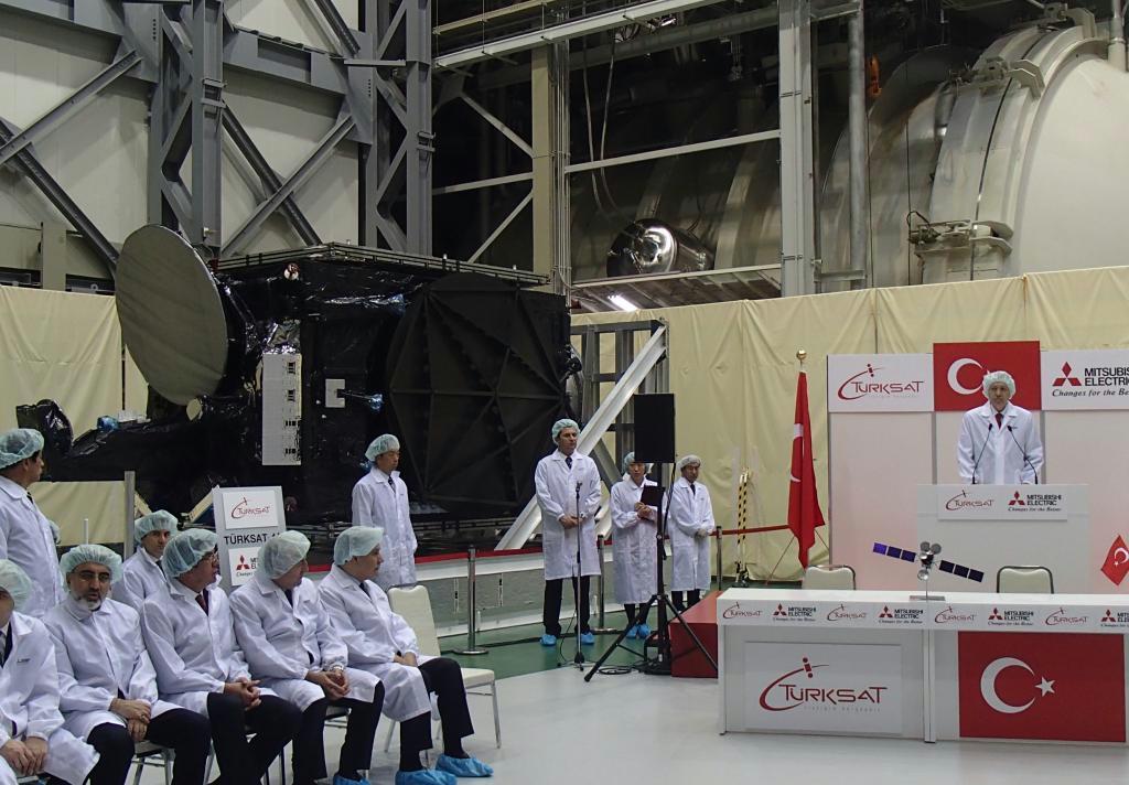 通信衛星（左奥）を前に壇上であいさつするトルコのエルドアン首相（右）＝神奈川県鎌倉市の三菱電機鎌倉製作所