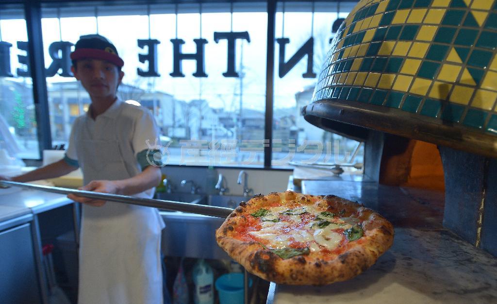 薪窯でピッツアを焼くピッツアイオーロの山田裕太さん。窓の外は北山通り＝２０１３年１２月１９日、京都市左京区（榎本雅弘撮影）