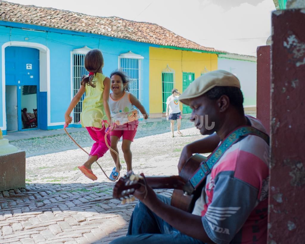 トリニダの広場近くでギターの練習に励む男性。そこに縄跳びで遊ぶ子どもたちが加わり賑やかになった＝キューバ（緑川真実さん撮影）
