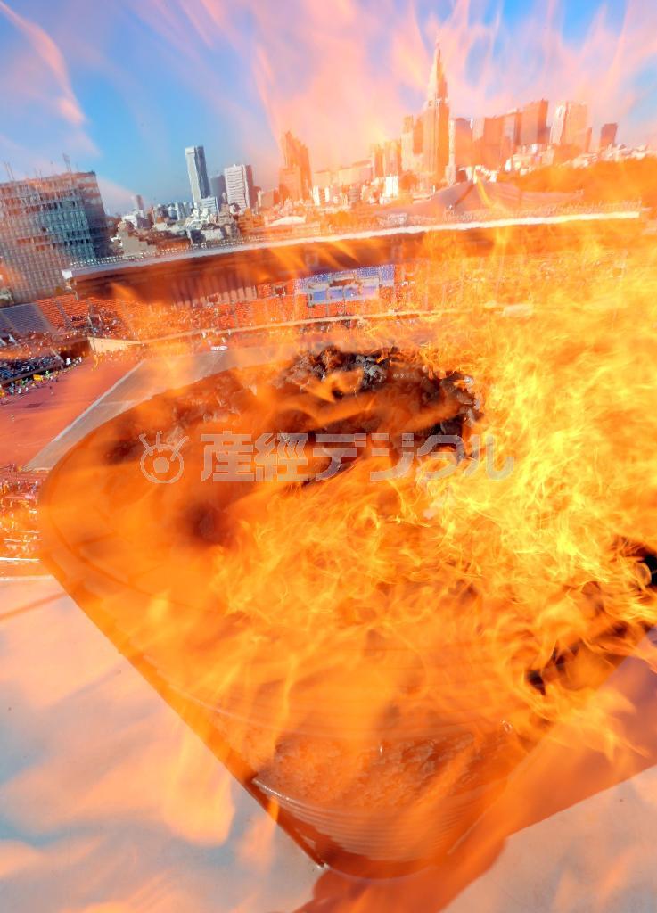 勢いよく燃え盛る聖火の向こうに広がる新宿副都心など東京の町並み＝２０１３年１２月１５日、東京都新宿区・国立競技場（鈴木健児撮影）