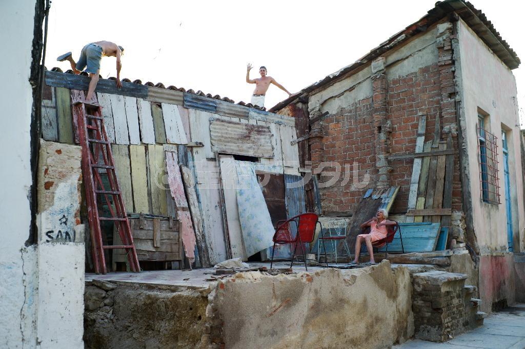 サンティアゴ・デ・キューバでハリケーンの被害にあった家を修理する男性。カメラを向けると手を振ってきた＝キューバ（緑川真実さん撮影）