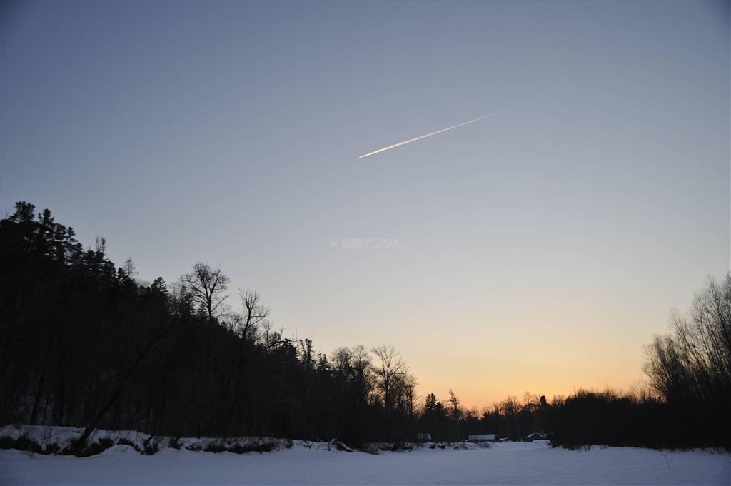 夕暮れのタイガの空を飛行機が飛んでいった。川辺の狩小屋での夕食が楽しみだ＝２０１１年２月２１日、ロシア・クラスヌイ・ヤール村（伊藤健次さん撮影）