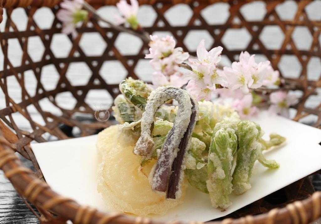 ふきのとうやタラの芽、新玉ねぎなど春野菜の天ぷらは、桜の枝を添え、カゴに入れて「山菜採り」をイメージしている