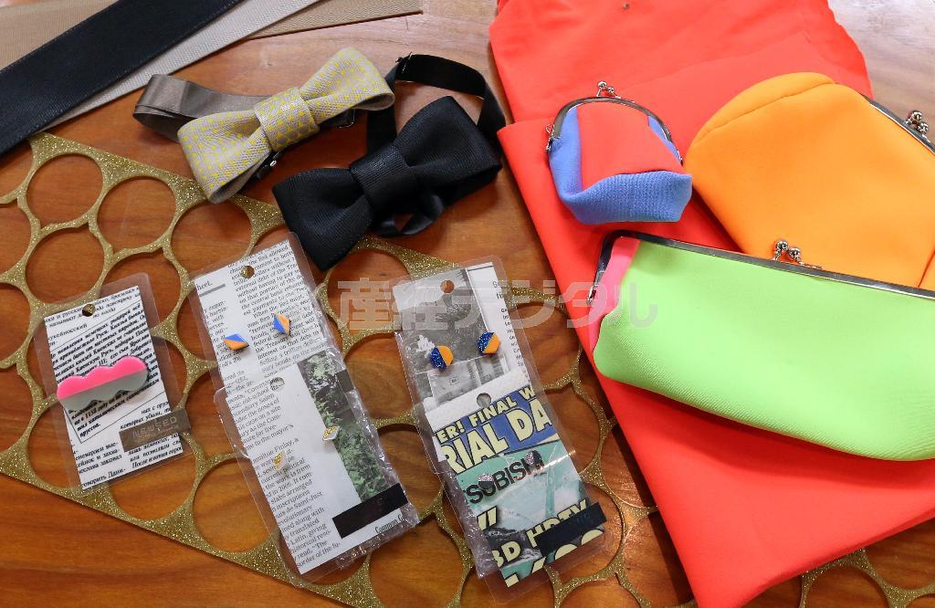 廃材を新たな視点でよみがえらせたＮＰＯ法人「ＮＥＷＳＥＤ＿ＰＲＯＪＥＣＴ（ニューズドプロジェクト）」の商品。髪留めやボタンを作るアクリル素材はバッジ（１６８０円）やピアス（２３１０円）、車のシートベルトは蝶ネクタイ（プレーン３８８５円、プリント４４１０円）、ウェットスーツの余った生地はポーチ（２６２５～３４６５円）