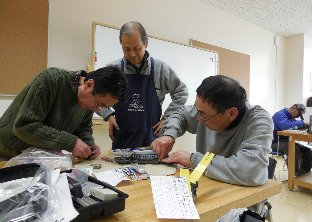 真剣な表情でおもちゃの修理を体験する相馬洋司さん（左）と大杉則夫さん（右）＝東京都江東区の「グランチャ東雲」
