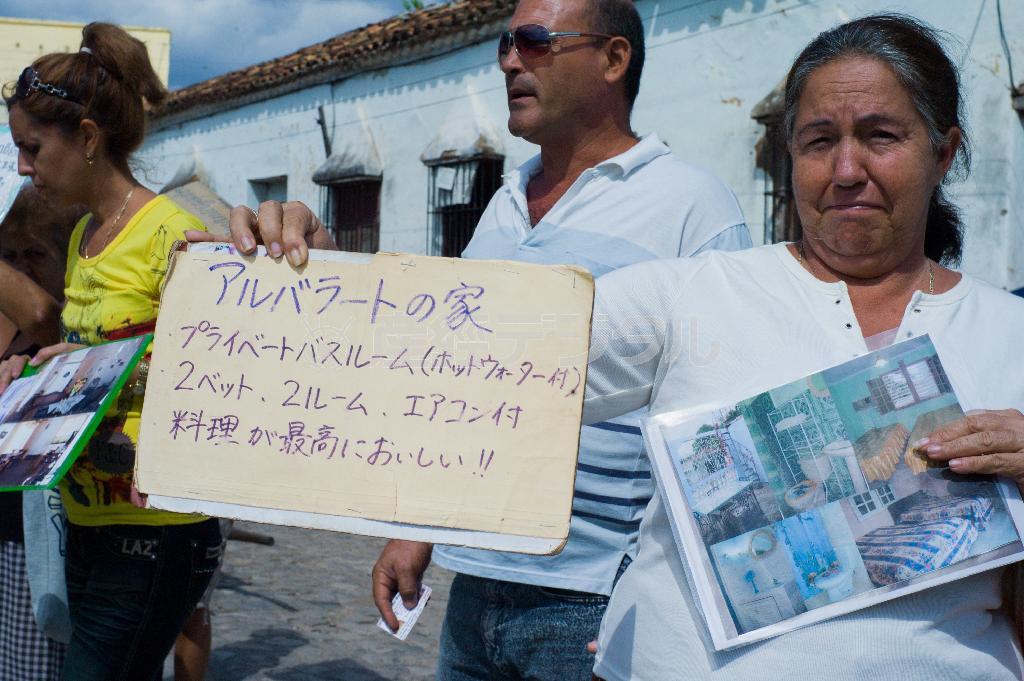 日本語で書かれた看板を持つ客引きの女性。異国で母国語を発見するとつい惹かれてしまう＝キューバ・トリニダ（緑川真実さん撮影）