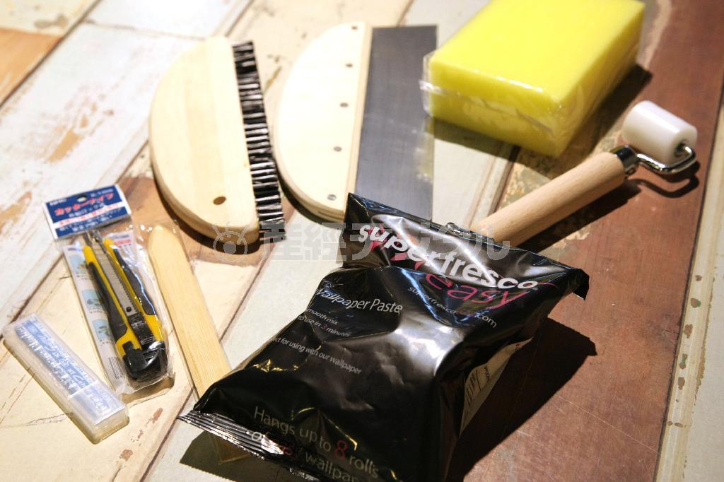 初心者用キットのこれだけあれば貼れちゃうセット（１９８０円）。地べら、なではけ、カッター、ローラーなどがセットされている。水で溶いて使うのり（７１０円）は別売り