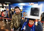 日本国内では３カ月遅れで発売された「プレイステーション４」。行列に並んで購入した子供たちは高々と“戦利品”を掲げた＝２月２２日、大阪市浪速区