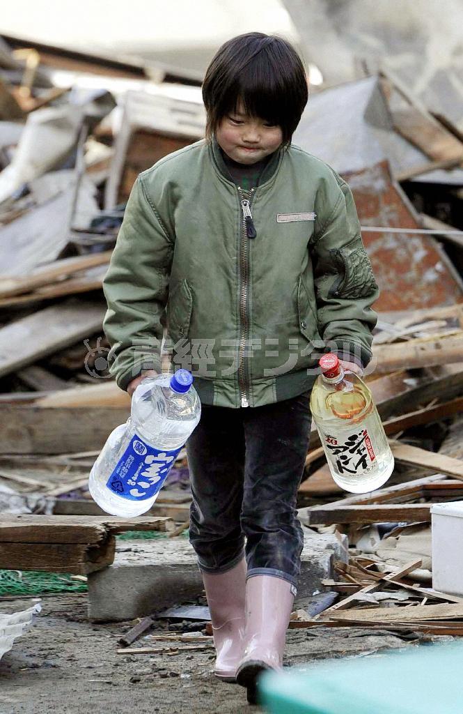 がれきの中、一生懸命水を運ぶ松本魁翔君。この写真は「水をくむ少年」というタイトルで国内外の新聞に掲載され、俳優の高倉健さんの心をも動かした＝２０１１年３月１４日、宮城県気仙沼市（共同）