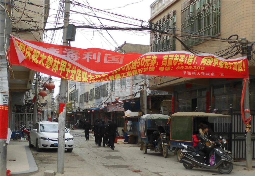 博社村では警察官が巡回する光景をしばしば見かけた。路地には覚醒剤撲滅の横断幕を隠すように、地元雑貨店の広告が掲げられていた＝２０１４年２月４日、中国・広東省汕尾市（矢板明夫撮影）