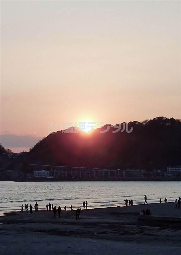 たくさんの人がその夕日を撮ろうと砂浜でカメラを構えている＝２０１４年３月９日、神奈川県鎌倉市の由比ガ浜