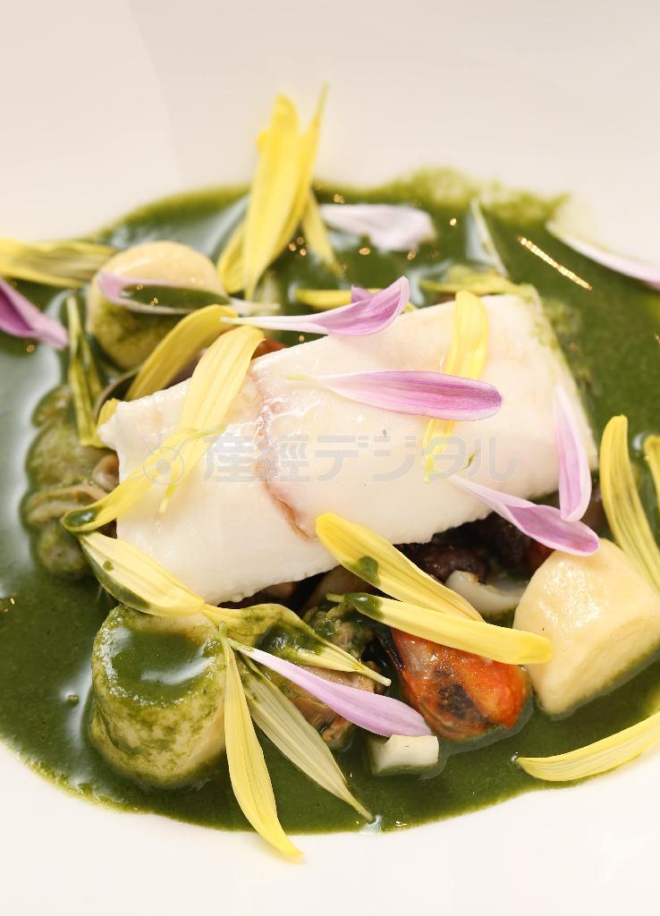 目の前でかけられる鮮やかな緑色の菊菜のソースと菊の花びらが春らしい「ひらめのプレゼ（蒸し煮）」